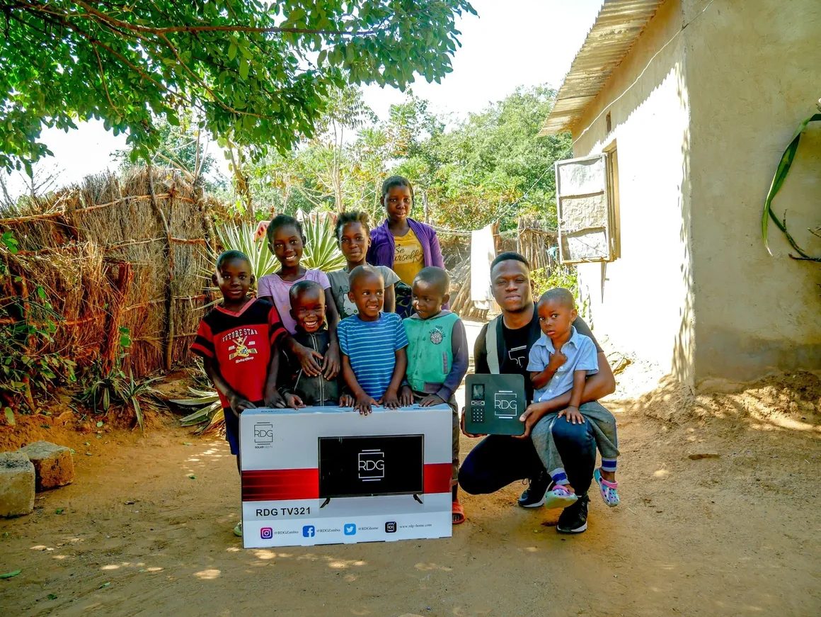 Group poses with RDG TV box and solar system outdoors.