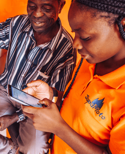 Two people looking at a smartphone, woman in SupaMoto shirt.